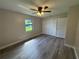 Bedroom with wood-look flooring, ceiling fan, closet, and a window offering natural light at 11681 Se 72Nd Court Rd, Belleview, FL 34420