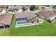 Aerial view of a private backyard featuring a screened-in pool and well-kept lawn at 12407 Ne 48Th Loop, Oxford, FL 34484