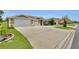 Beautiful home exterior featuring a large driveway, palm tree, and well manicured lawn at 12407 Ne 48Th Loop, Oxford, FL 34484