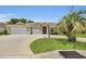 Charming single-story home featuring a well-manicured lawn, mature palm tree, and a spacious three-car garage at 12407 Ne 48Th Loop, Oxford, FL 34484