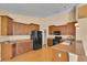 Bright kitchen featuring wood cabinets, a black refrigerator, and a granite countertop at 12407 Ne 48Th Loop, Oxford, FL 34484