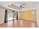 Bright living room with a tray ceiling, fan, and sliding glass doors to the pool area at 12407 Ne 48Th Loop, Oxford, FL 34484