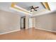 Spacious main bedroom boasts a tray ceiling with a fan, neutral paint, and wood-look flooring at 12407 Ne 48Th Loop, Oxford, FL 34484