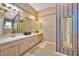 Well-lit bathroom with double sinks, a shower, decorative wallpaper, and ample counter space at 1401 Madrigal Ln, Lady Lake, FL 32159