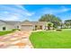 Charming single-story home with well-manicured lawn, colorful driveway, and attached two-car garage at 1401 Madrigal Ln, Lady Lake, FL 32159