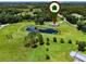 Aerial view of property with pond and outbuildings surrounded by green pastures and lush trees at 14325 Manchester Ave, Groveland, FL 34736