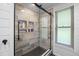Bathroom shower featuring stylish tiles, glass doors, and a window for natural light at 14325 Manchester Ave, Groveland, FL 34736