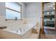 This bright bathroom has a soaking tub next to a frosted window and an open doorway to the bedroom at 14325 Manchester Ave, Groveland, FL 34736