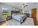 Cozy bedroom featuring a rustic wood headboard, ceiling fan, and scenic views from large windows at 14325 Manchester Ave, Groveland, FL 34736