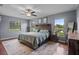 This primary bedroom has a wood headboard, a ceiling fan, and windows overlooking the yard at 14325 Manchester Ave, Groveland, FL 34736