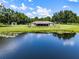 The tranquil pond reflects the sky, enhancing the beauty of the home's lush backyard at 14325 Manchester Ave, Groveland, FL 34736