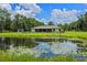 Expansive backyard features a serene pond with lily pads, lush greenery, and a charming home exterior at 14325 Manchester Ave, Groveland, FL 34736