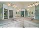 Elegant bathroom featuring double sinks, marble countertops, vanity mirrors, and updated fixtures at 1512 Cervantes Pl, Lady Lake, FL 32159