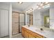 Bathroom featuring dual sinks, wooden cabinets, vanity lighting, and walk-in shower at 1512 Cervantes Pl, Lady Lake, FL 32159