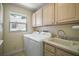 Functional laundry room features a washing machine, dryer, utility sink, and ample cabinet storage at 1512 Cervantes Pl, Lady Lake, FL 32159