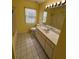 Bright yellow bathroom featuring a single sink vanity, neutral tile flooring, and natural light at 17329 Se 115Th Ter, Summerfield, FL 34491