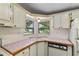 Bright kitchen corner with classic cabinets, tile countertops, and double windows overlooking the yard at 1855 Stacey Dr, Mount Dora, FL 32757