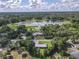 This aerial view showcases houses near a lake and mature trees against a backdrop of cloudy skies at 2450 W Lake Dr, Deland, FL 32724