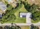 An aerial view of a home with a metal roof, solar panels, a driveway, and surrounding greenery at 2450 W Lake Dr, Deland, FL 32724
