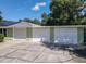 Exterior of home showing three-car garage, concrete parking area, and sage green brick at 2450 W Lake Dr, Deland, FL 32724