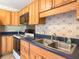 Close-up view of kitchen featuring wood cabinets, double basin sink, and black appliances at 2450 W Lake Dr, Deland, FL 32724