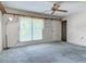 Cozy living room with a ceiling fan, large window, and neutral-colored walls and carpet at 2450 W Lake Dr, Deland, FL 32724