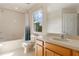 Bright bathroom featuring a tub with shower, toilet, vanity with sink, and large window at 2717 Bushman Dr, Kissimmee, FL 34746
