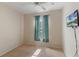 An empty bedroom with a ceiling fan, neutral carpet, a window with curtains, and a wall-mounted TV at 2717 Bushman Dr, Kissimmee, FL 34746