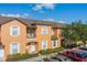 An inviting orange two-story townhome with a balcony, white trim, and landscaped frontage and parking at 2717 Bushman Dr, Kissimmee, FL 34746