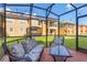 A view of the relaxing screened patio with a cushioned couch and chair and a table for outdoor relaxation at 2717 Bushman Dr, Kissimmee, FL 34746