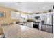Well-lit kitchen with stainless steel appliances, white cabinets, and large granite countertops at 3105 Carrollton Ct, The Villages, FL 32162