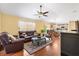 Open-concept living room with hardwood floors, ceiling fan, and comfortable leather furniture at 3105 Carrollton Ct, The Villages, FL 32162