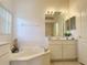 Bright bathroom featuring a soaking tub, vanity with sink, and a decorative mirror at 3416 Capland Ave, Clermont, FL 34711
