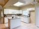 Well-lit kitchen featuring white cabinets, an island, and neutral countertops, with tile flooring at 3416 Capland Ave, Clermont, FL 34711