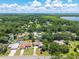 Scenic aerial view of a charming home in a lush, green community with a lake backdrop and sunny skies at 35338 Lake Unity Rd, Fruitland Park, FL 34731