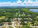 Scenic aerial view of a charming home in a lush, green community with a lake backdrop and sunny skies at 35338 Lake Unity Rd, Fruitland Park, FL 34731