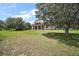 Back exterior view of the home, showing the covered patio and balcony, set on a sprawling lawn with mature trees at 36914 Bee Meadow Ct, Eustis, FL 32736