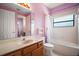 Well-lit pink bathroom with a vanity, toilet and tub/shower combination with neutral tile at 36914 Bee Meadow Ct, Eustis, FL 32736