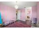 Spacious pink bedroom with a chandelier, hardwood floors and play furniture adjacent to bathroom and hallway at 36914 Bee Meadow Ct, Eustis, FL 32736