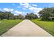 Long driveway leading to an elegant home surrounded by a lush green lawn and mature trees at 36914 Bee Meadow Ct, Eustis, FL 32736