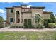 Elegant home with a stucco exterior, arched entrance, well-manicured landscaping, and a tile roof at 36914 Bee Meadow Ct, Eustis, FL 32736