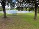 Bench overlooking a serene lake, surrounded by trees at 36914 Bee Meadow Ct, Eustis, FL 32736