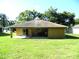 Backyard of the house featuring a covered patio, green lawn, and mature trees at 5016 Mcdonald Rd, Zellwood, FL 32798