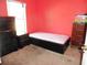 Standard bedroom featuring red walls, a single bed with black frame, and 2 dressers at 5016 Mcdonald Rd, Zellwood, FL 32798