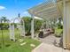 Inviting back patio with pergola, offering a relaxing outdoor living space with lush landscaping at 591 Allenwood Loop, The Villages, FL 32162