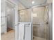 Modern bathroom featuring a tiled shower with glass doors and an open doorway revealing wood floors and a chandelier at 591 Allenwood Loop, The Villages, FL 32162
