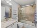 Full bathroom featuring a shower-tub combo with sliding glass doors and a marble-topped vanity at 591 Allenwood Loop, The Villages, FL 32162