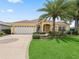 Well-maintained home featuring a lush front yard, palm trees, and a decorative circular driveway at 591 Allenwood Loop, The Villages, FL 32162