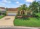 Charming yellow home showcasing a lush front yard with mature palm trees and a circular driveway at 591 Allenwood Loop, The Villages, FL 32162