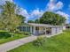 Charming home with sunroom, carport, and landscaped yard on a sunny day at 601 Jason Dr, The Villages, FL 32159
